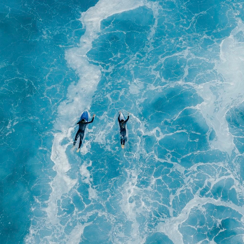 Two surfers paddling through turquoise waves – End of Summer Sale